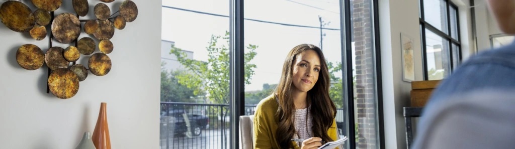 woman sitting in office in front of window with notepad and pen