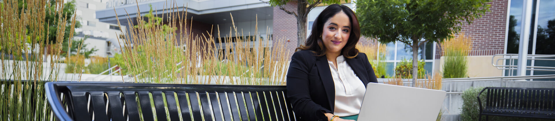 Balkis N. sitting on bench in front of an office