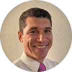 Headshot of Dr. Brian Tilley, PhD, MA in Counseling Associate Professor & Program Director, a clean-shaven man in a white shirt and printed tie