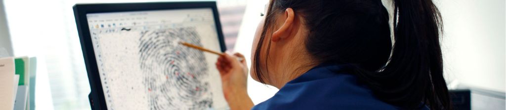woman analyzing a large fingerprint on a computer