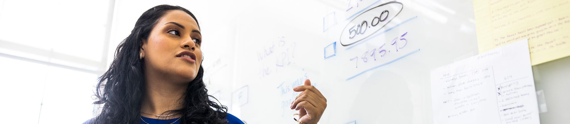 A woman teaches at a whiteboard. Minor in Business Admin Program Page