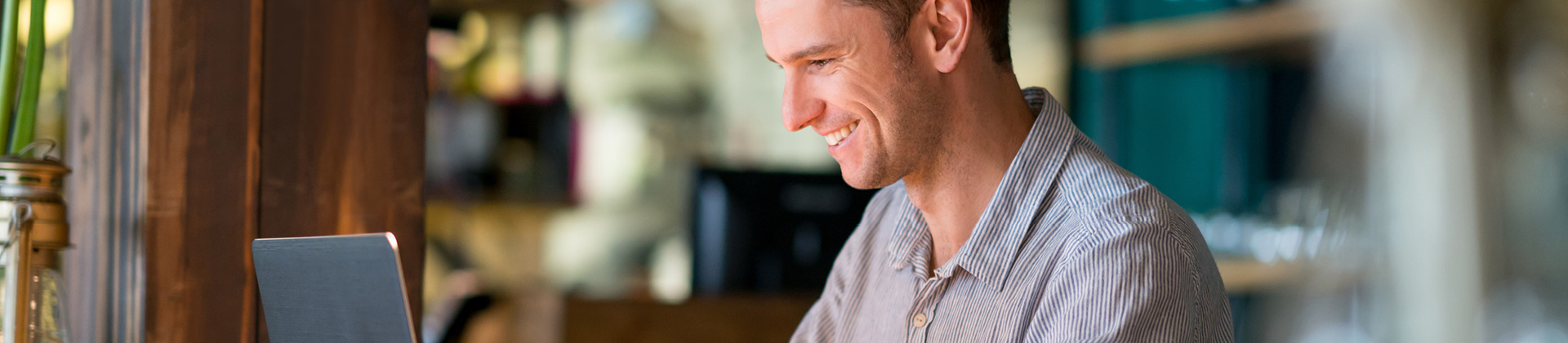 man smiling as he gazes at a laptop 