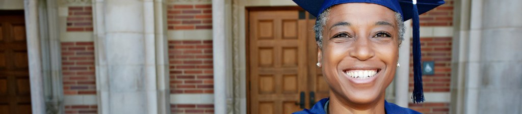 Person smiling after receiving her MBA  wearing graduation cap and gown 