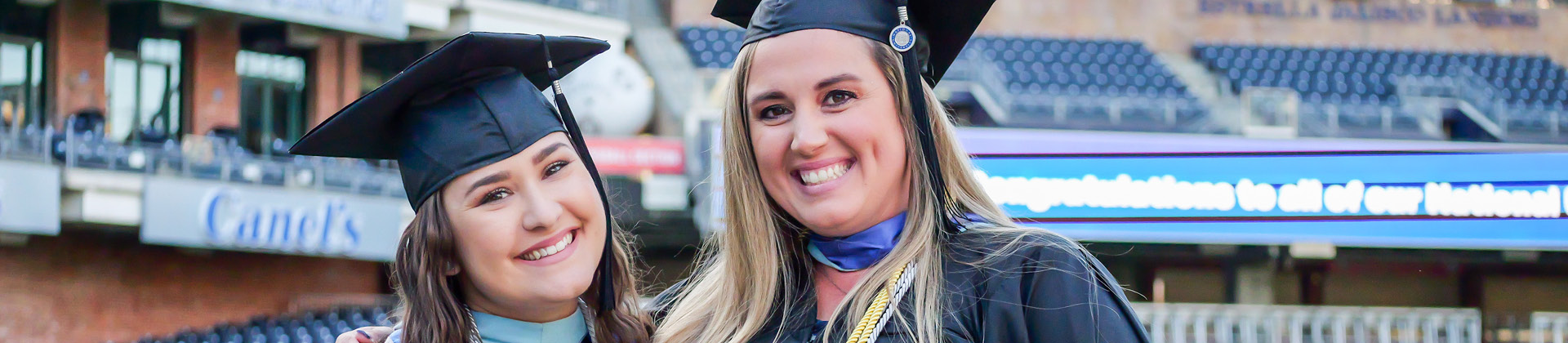 Two women dressed in regalia at their commencement 