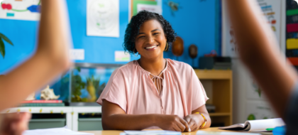 teacher in classroom with kids raising their hands