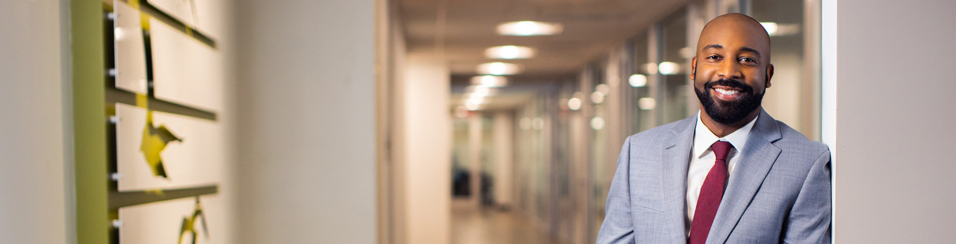 Man in a light grey suit stands in a hallway