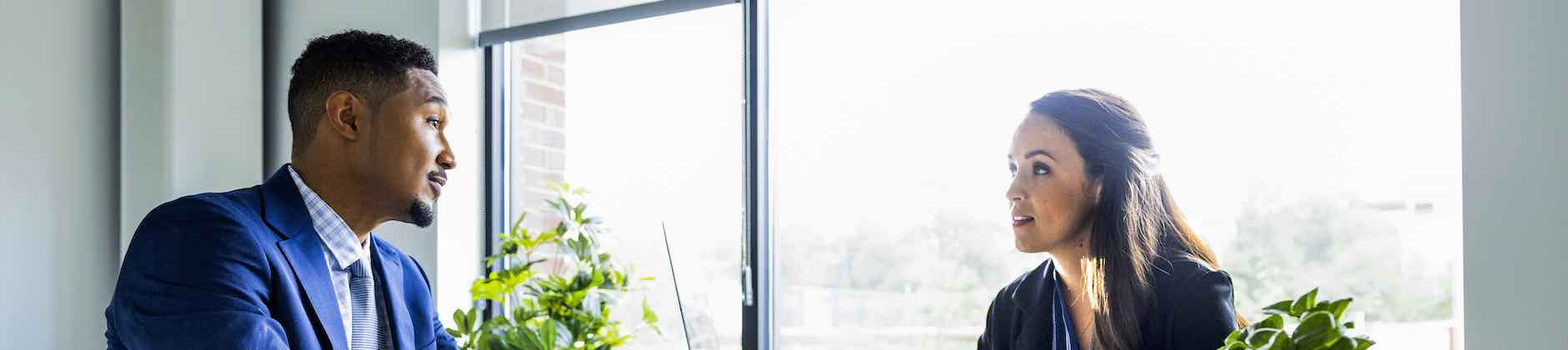 two people talking in an office in front of a window