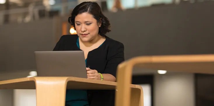 Woman sitting in library working on laptop